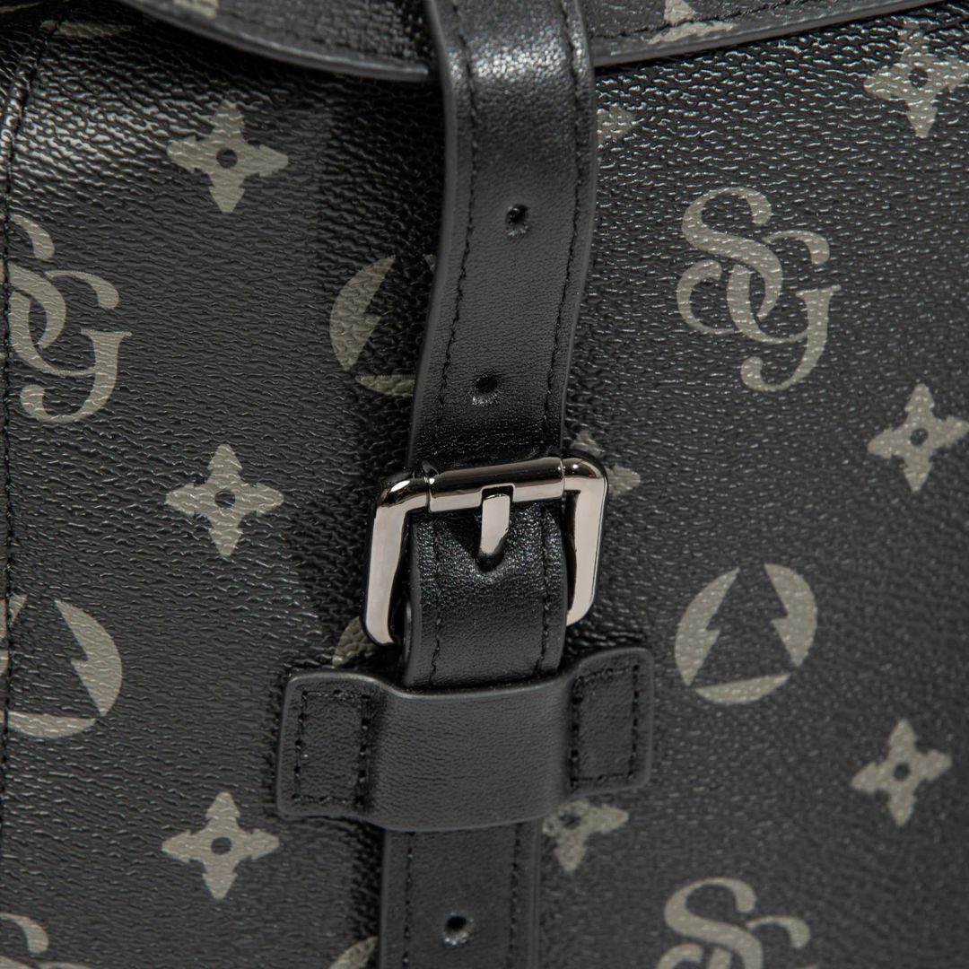Close-up of a black leather bag with a patterned strap and buckle.