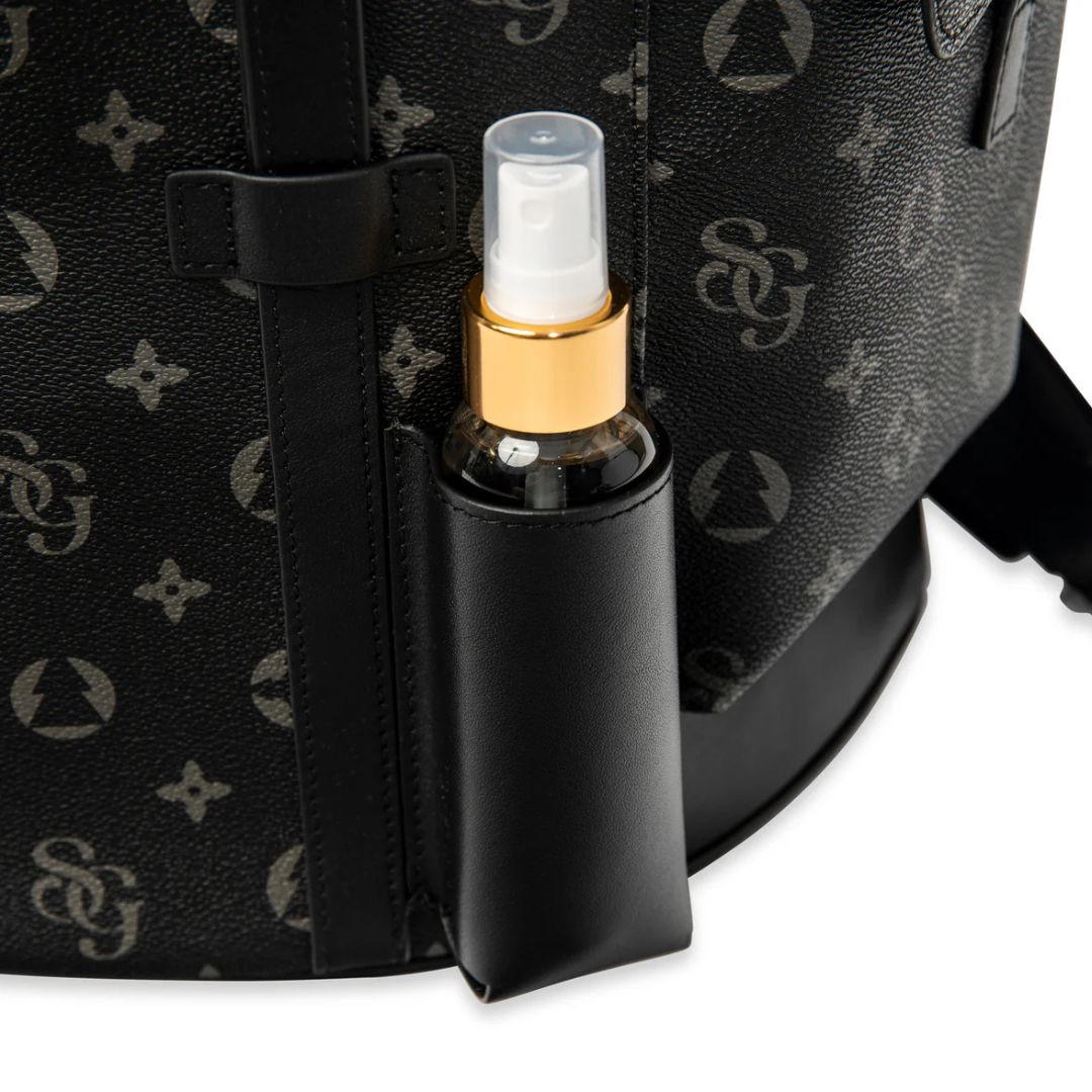 Black spray bottle with gold nozzle attached to a black patterned bag