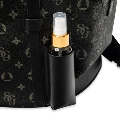 Black spray bottle with gold nozzle attached to a black patterned bag