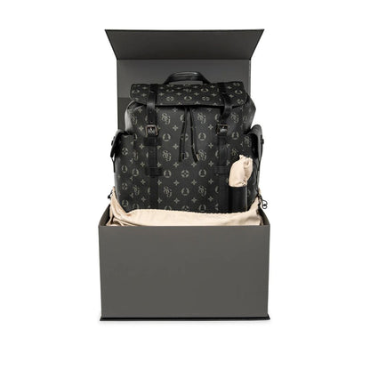 Black patterned backpack in an open gray box on a white background