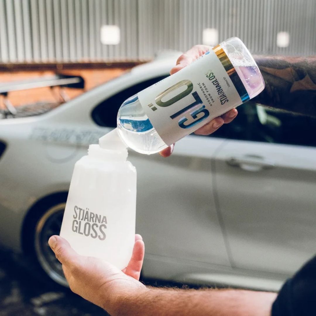 Person holding a bottle of StärnaGloss glo in front of a car.