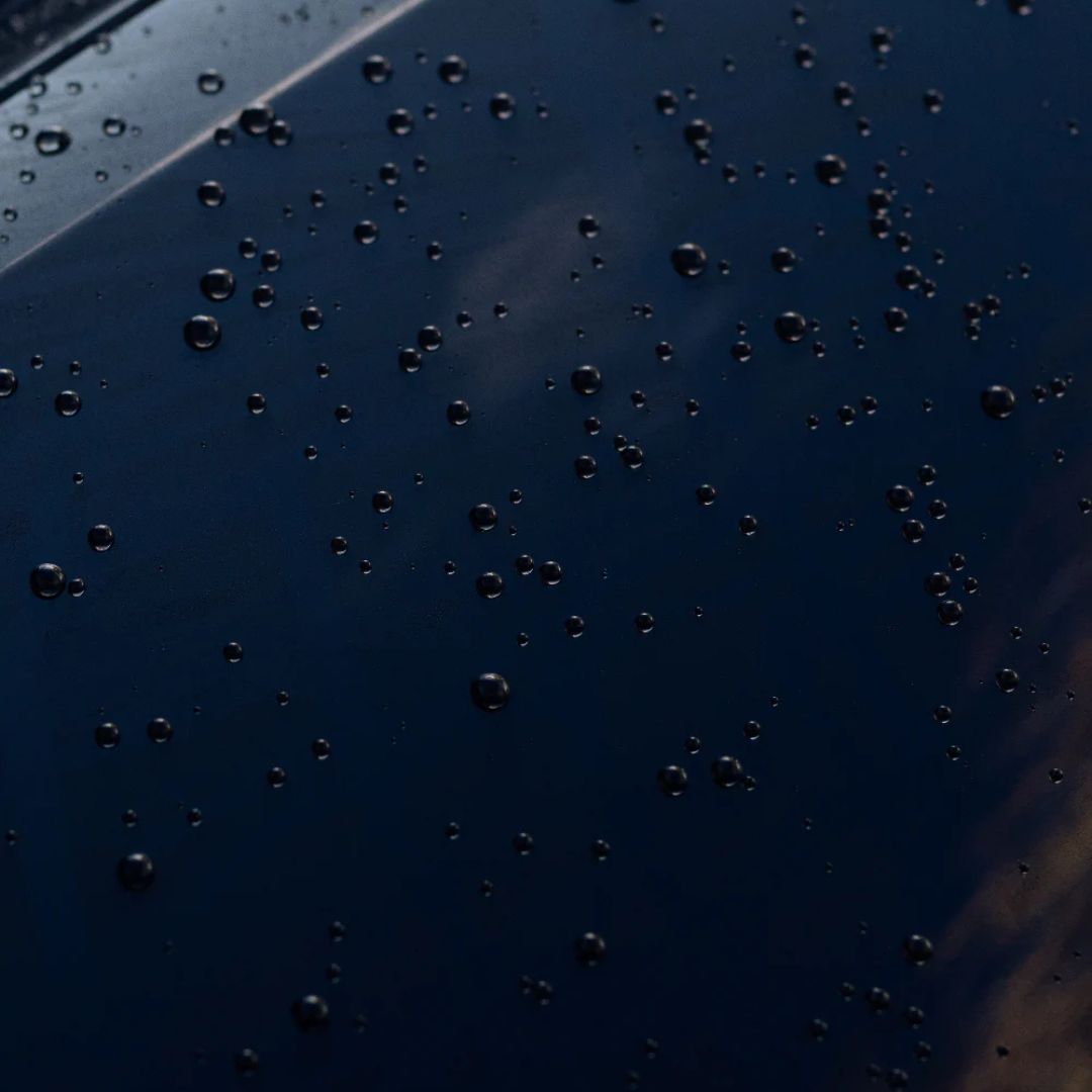 Close-up of water droplets and beading on a dark surface