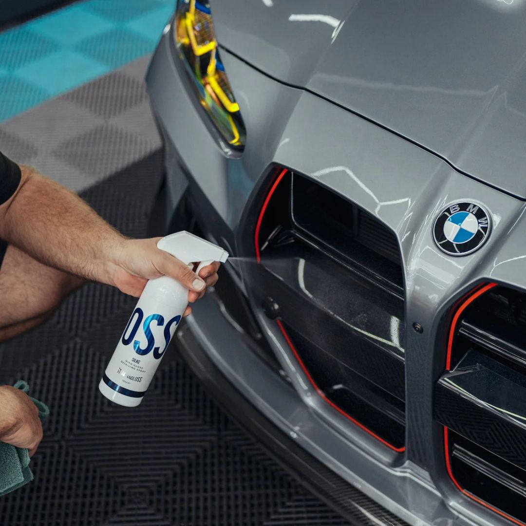 Person cleaning a BMW M3 car with a spray bottle labeled 'Silke'.