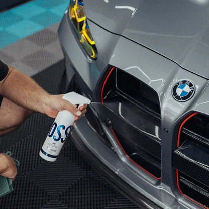 Person cleaning a BMW M3 car with a spray bottle labeled 'Silke'.