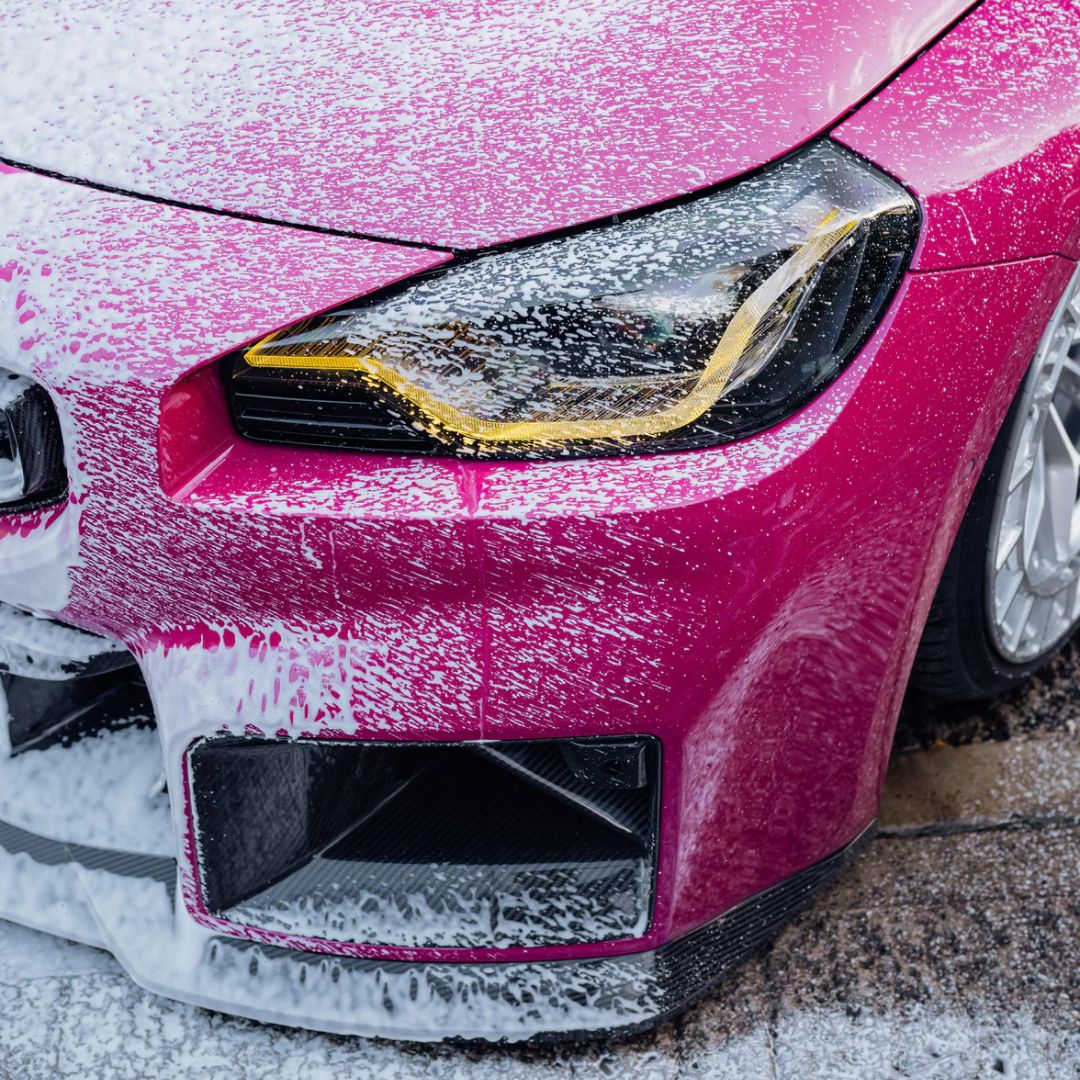 Close-up of a pink BMW M2 headlight with Stjarnagloss Sno - pH-Neutral Snow Foam on pink BMW M2