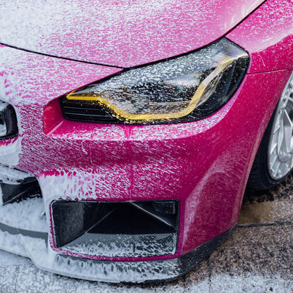 Close-up of a pink BMW M2 headlight with Stjarnagloss Sno - pH-Neutral Snow Foam on pink BMW M2
