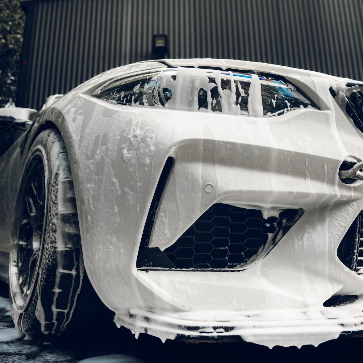 Car with soap suds on a BMW M2 on a soapy wash, outdoors.