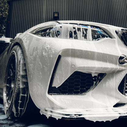 Car with soap suds on a BMW M2 on a soapy wash, outdoors.