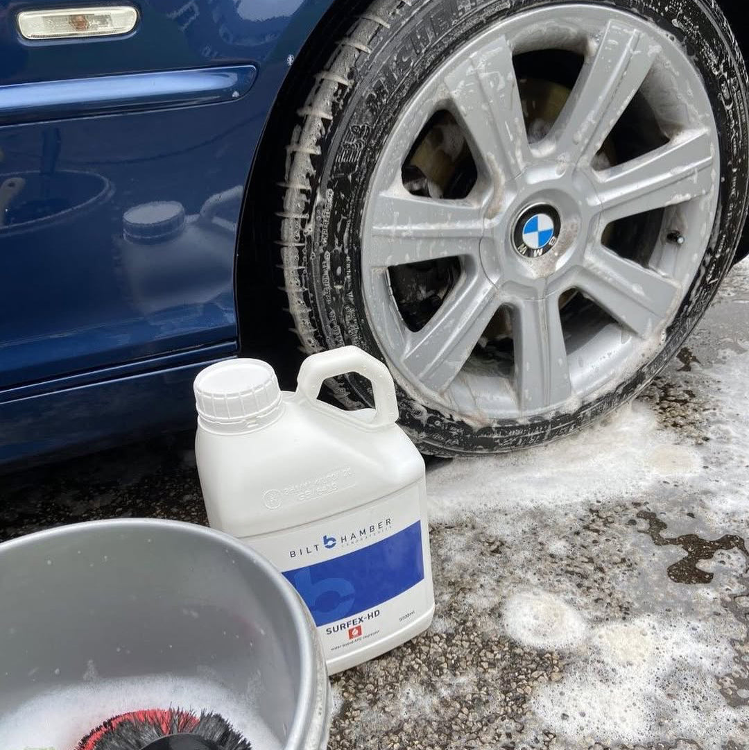 Car cleaning process with a bottle of Bilt-Rite cleaner next to a BMW car tire.