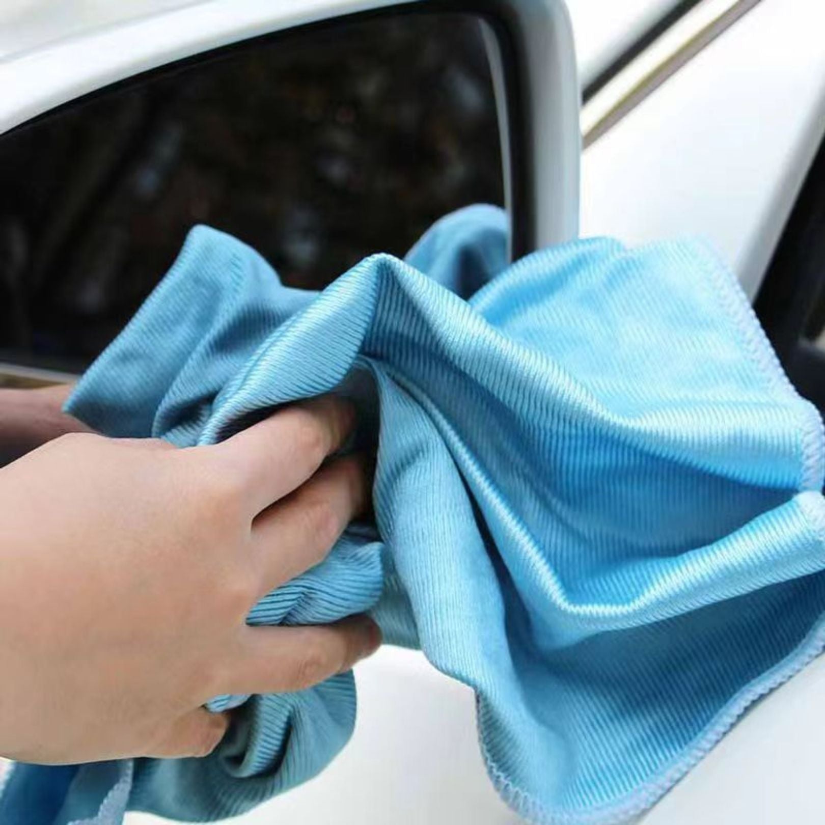 Person cleaning a car window with a blue microfibre glass cloth washme.ie branded