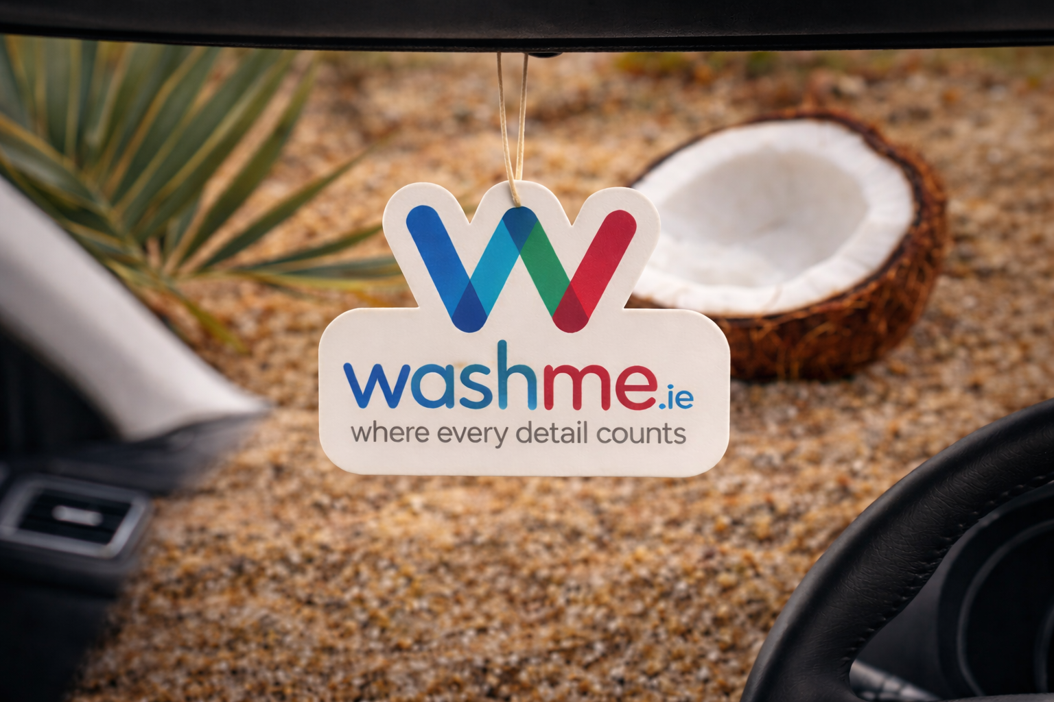 Coconut Car air freshener with 'washme.ie' logo hanging from a car's rearview mirror.
