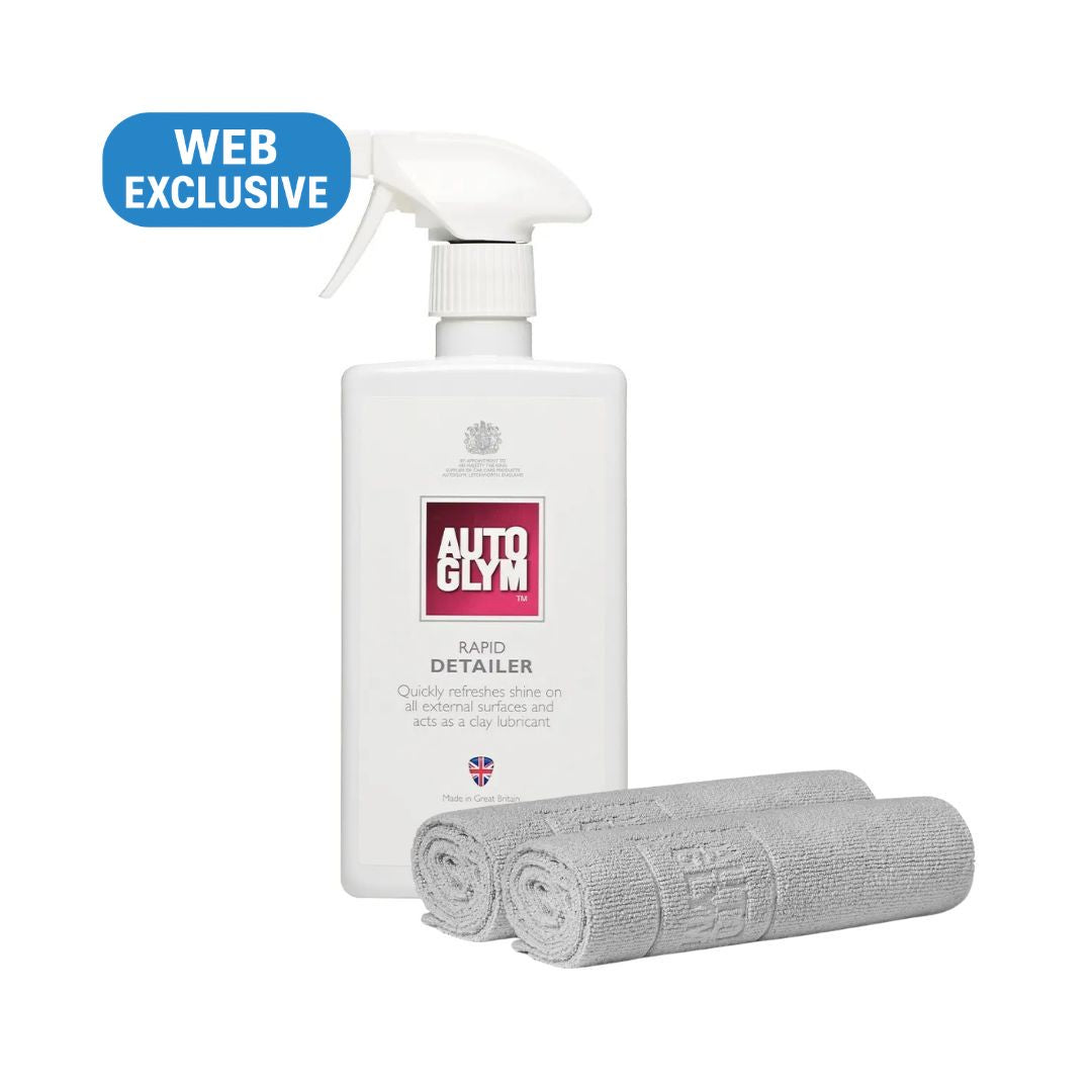 A white bottle of Autoglym Rapid Detailer spray with a trigger sprayer, shown alongside two rolled gray microfibre towels on a plain white background. A blue 'WEB EXCLUSIVE' badge is in the top-left corner.