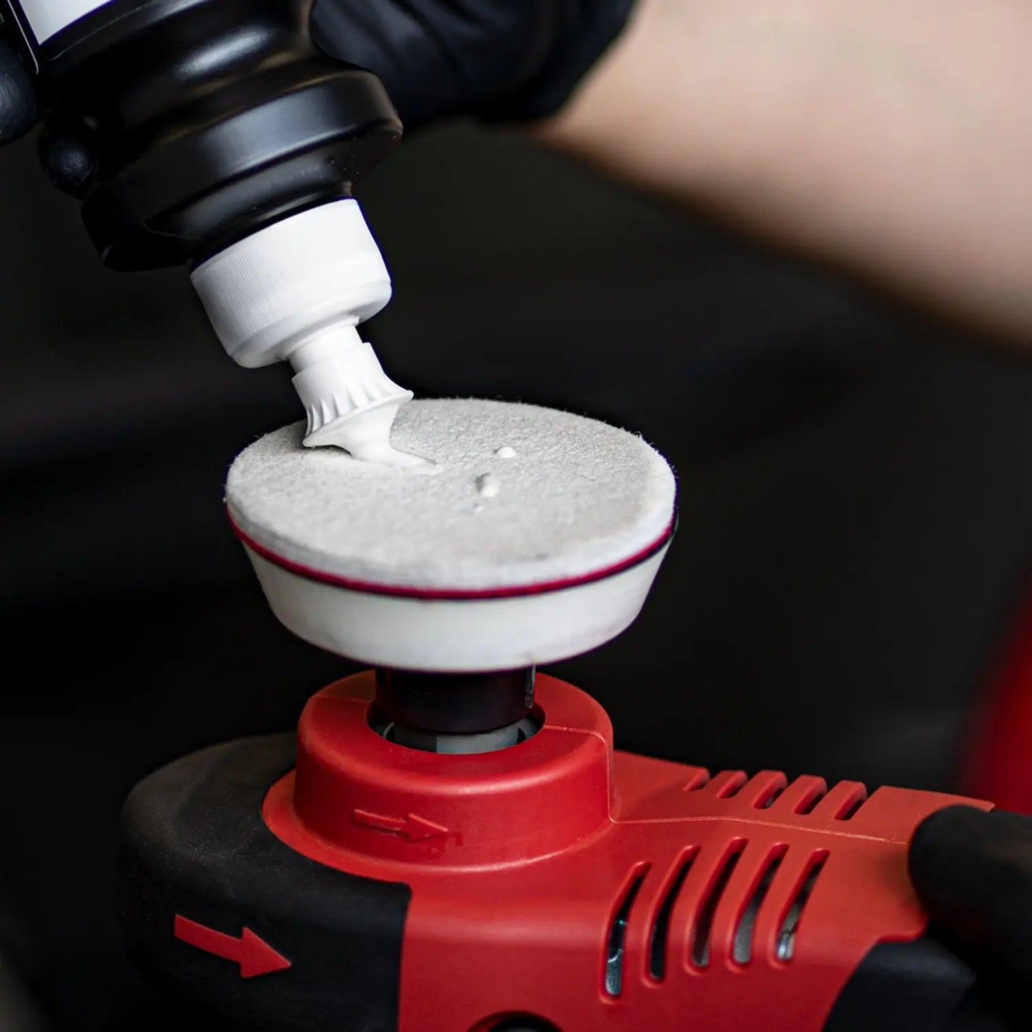 Person applying white paste to a red and black polisher.