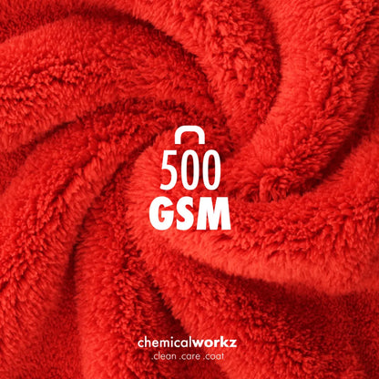A close-up of bright red plush microfibre with a visible texture, arranged in a swirl pattern. White text in the center reads '500 GSM', and near the bottom reads 'chemicalworkz clean care coat'.