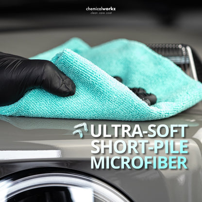 Turquoise microfiber towel with black glove holding it, on a car surface, with 'chemicalworkz' branding.