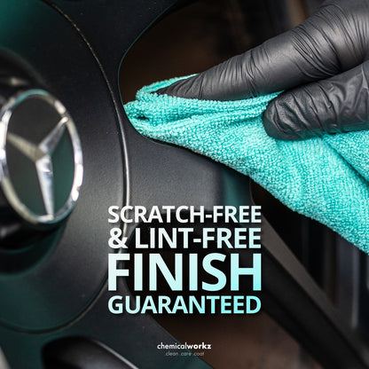 Hand wearing a black glove cleaning a car emblem with a teal cloth, text 'Scratch-Free & Lint-Free Finish Guaranteed' and brand 'chemicalworkz'.