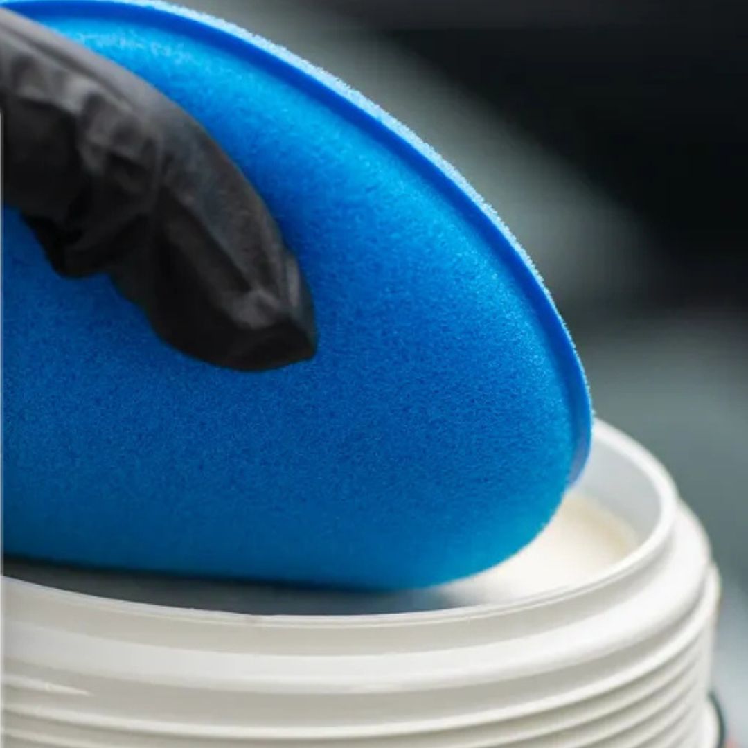 Blue applicator disc on a white container with a blurred background