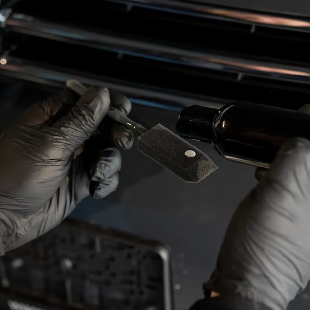 Person wearing gloves using a swab on a vehicle's air conditioning system.