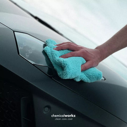 Person cleaning a car window with a teal microfiber cloth, featuring 'chemicalworkz' branding.