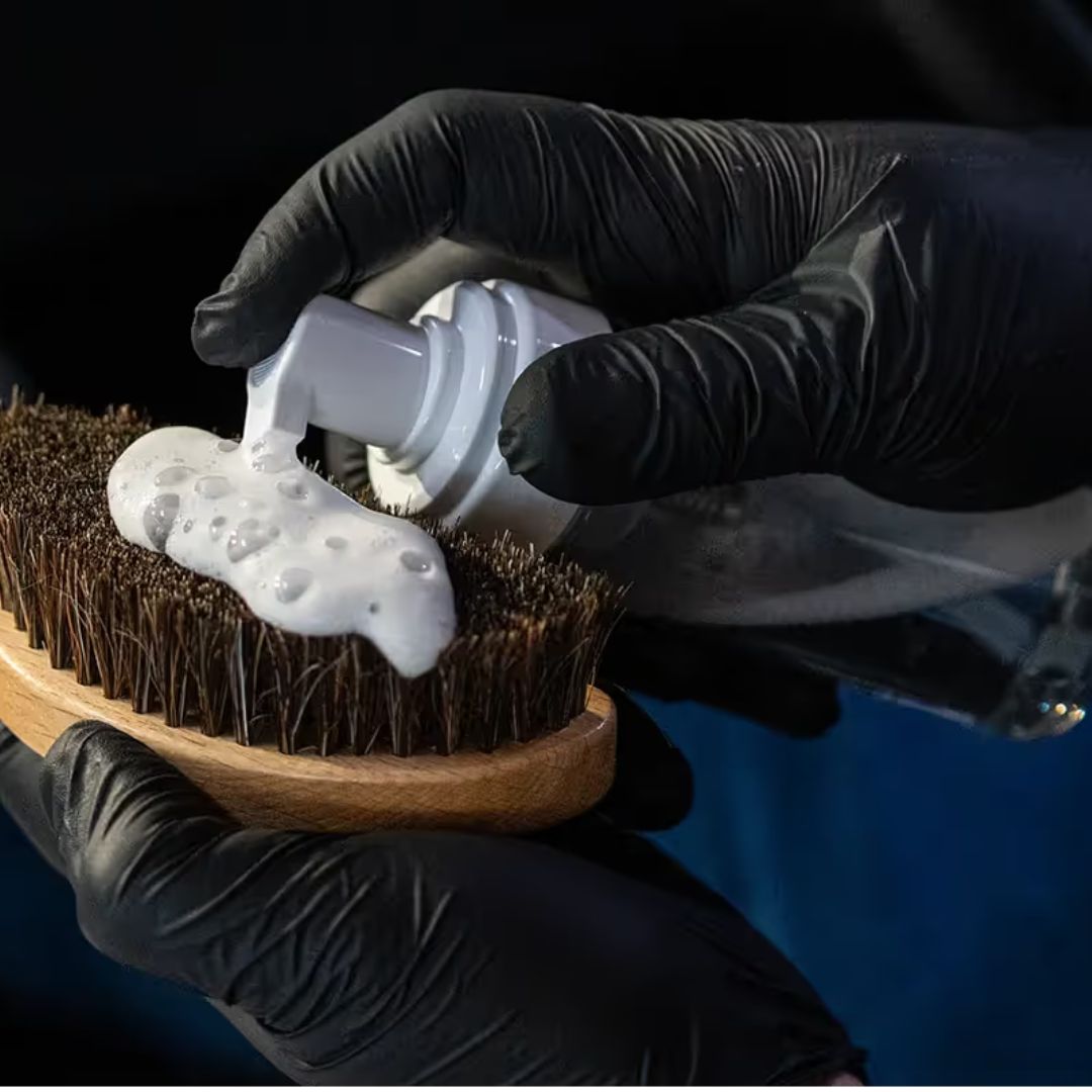 chemicalworkz Foam bottle. Person applying white foam to a wooden brush with black gloves on a dark background