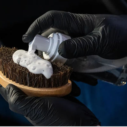 chemicalworkz Foam bottle. Person applying white foam to a wooden brush with black gloves on a dark background