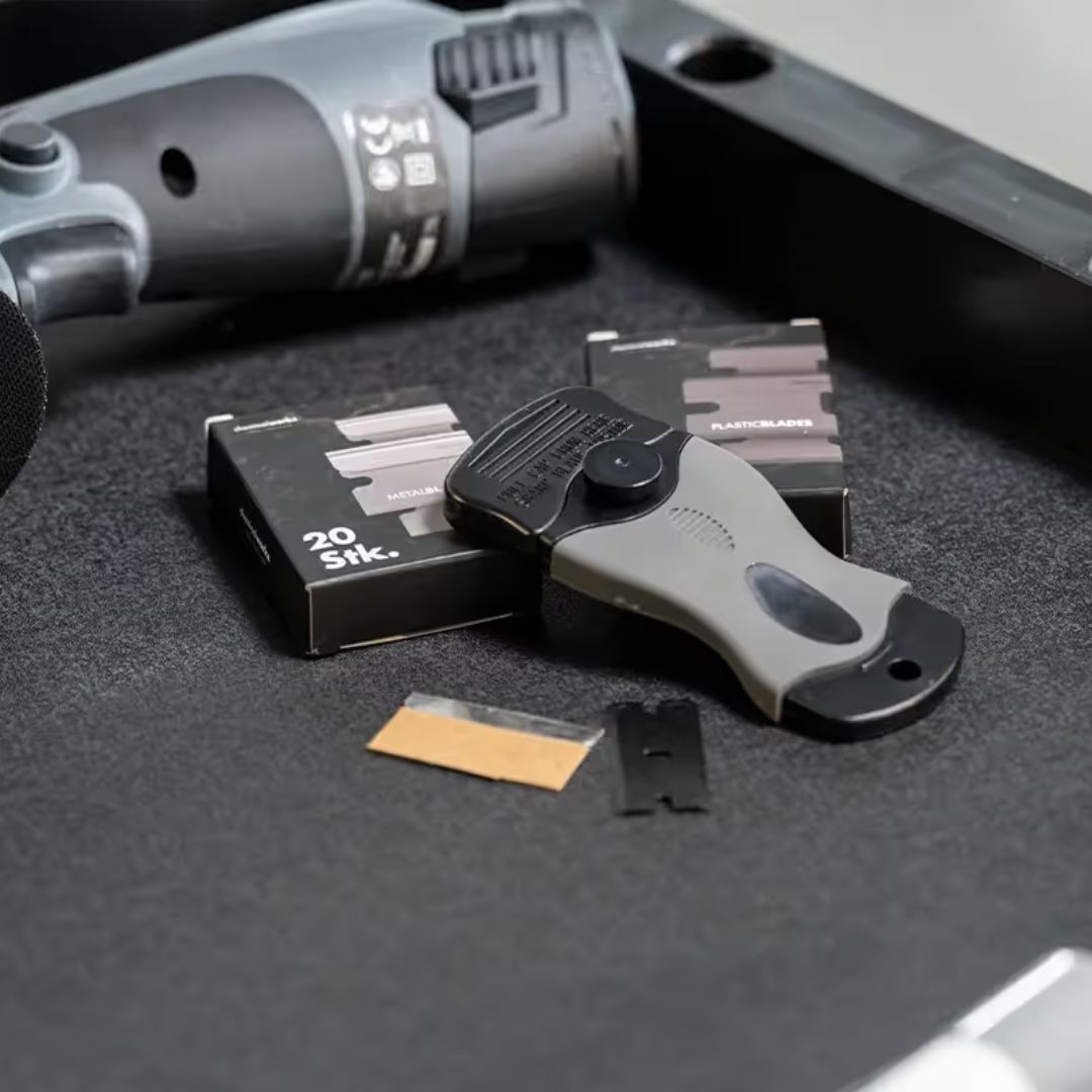 plastic and metal scraper with blades on a dark surface
