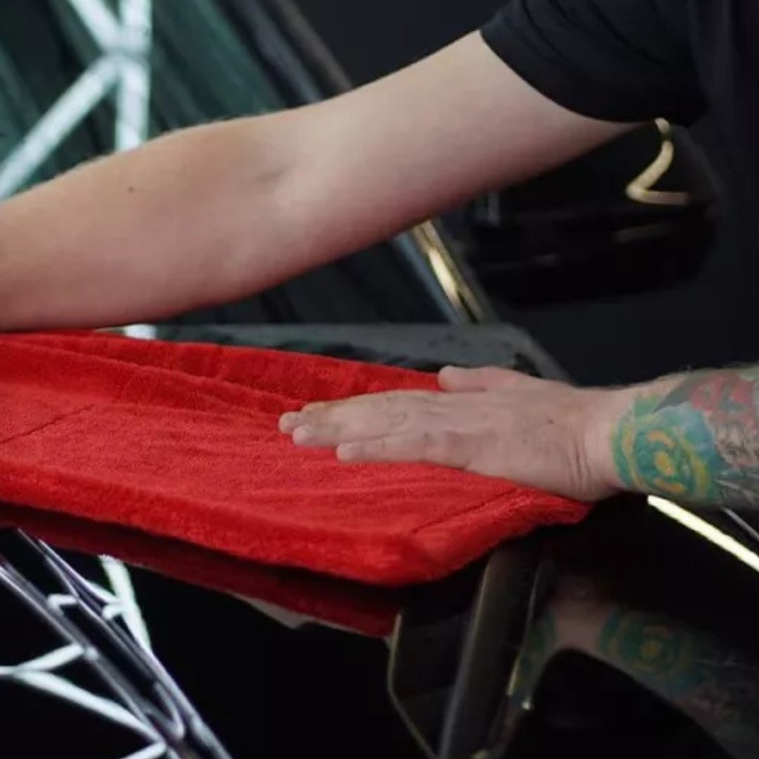 Person drying a car with a red chemicalworkz drying towel