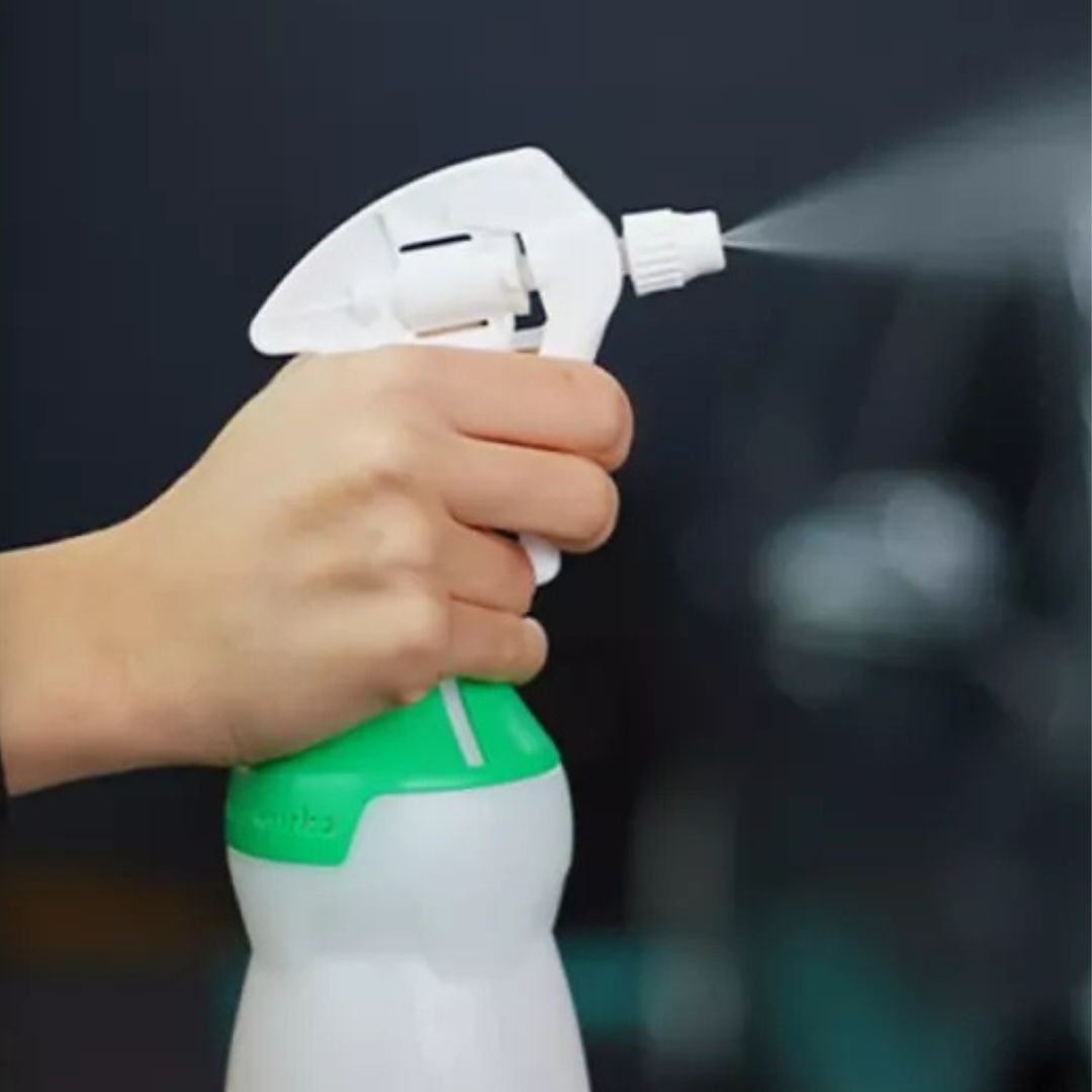 Hand holding a white and green spray bottle from chemworkz with a dark background