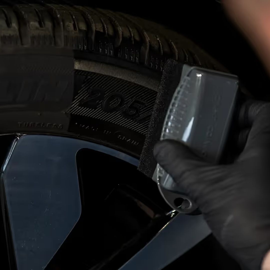 Person wearing a black glove holding a tyre dressing applicator