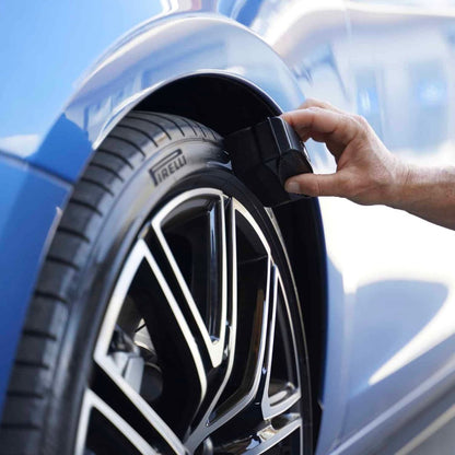 Person applying tire sealant to a car tire with a blue car in the background